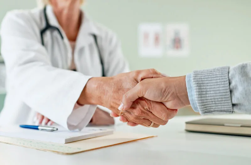 A primary care physician shakes hands with a patient in a doctor’s office in North Texas